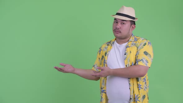 Stressed Young Overweight Asian Tourist Man Showing Something