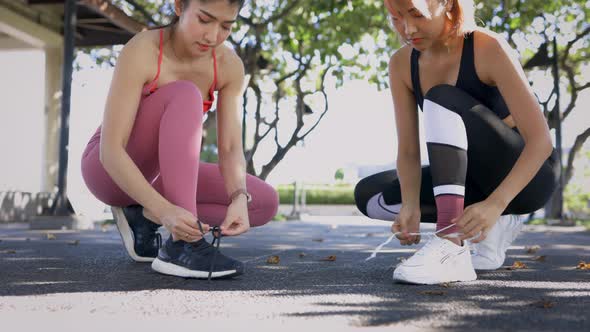 Young Asian Female Runners in Park Tying Shoe Lace