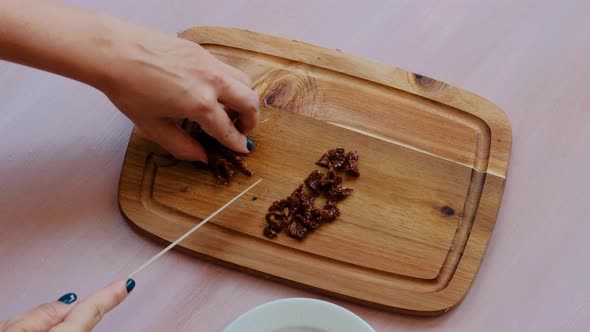 Top view of woman hands with knife cutting smoked tomatoes for salad on a wooden board