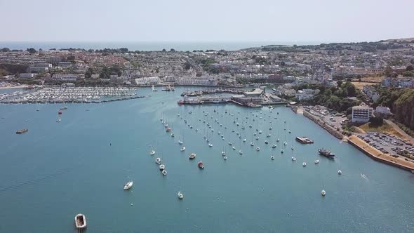 Aerial footage of a large seaside port community surrounding a marina used by yachts and sailboats.