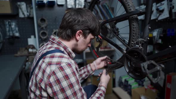 A Cycle Technician Fixes the Bicycle Chain with a Special Work Tool at the Cycling Service Center