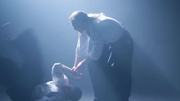 Fight Between Two Aikido Fighters in Dark Studio with Smoke and Lighting. Slow Motion. Close Up.