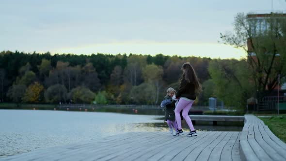 Happy Mom Walks with Her Daughter in the Autumn Park