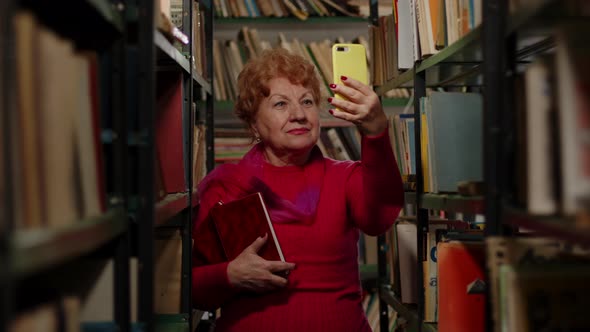 An Elderly Woman Takes a Photo with Books in the Library