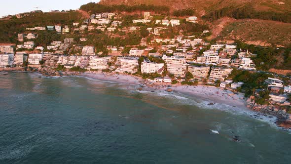 Clifton beach coastline full of tourists and hotels in Cape Town at sunset, aerial