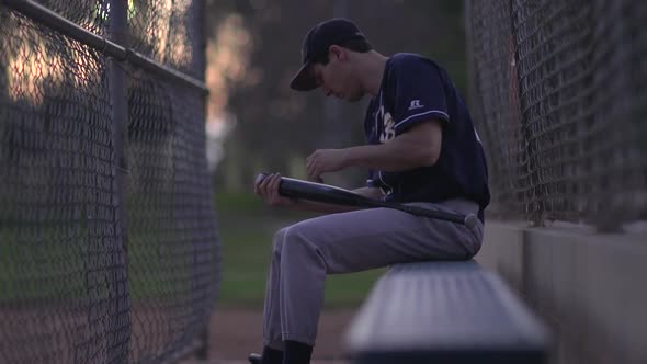 A baseball player resting on the bench.