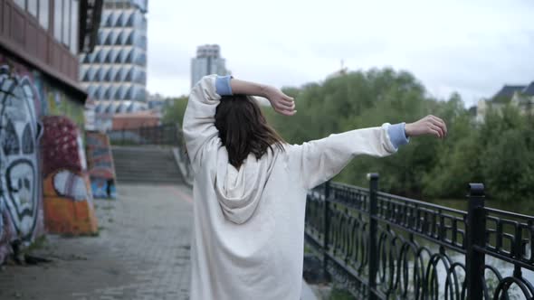 Beautiful Girl Whirls on the Embankment Walking Along the Fence