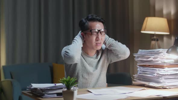 Tired Asian Man Shaking His Head While Working Hard With Documents At The Home