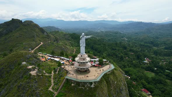 Aerial of a Jesus Christ Statue in Tana Toraja Sulawesi at the top of a mountain with tourists and s