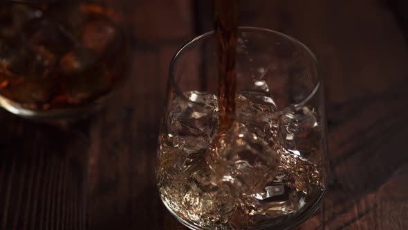 Camera follows pouring whiskey into a glass. Slow Motion. alt