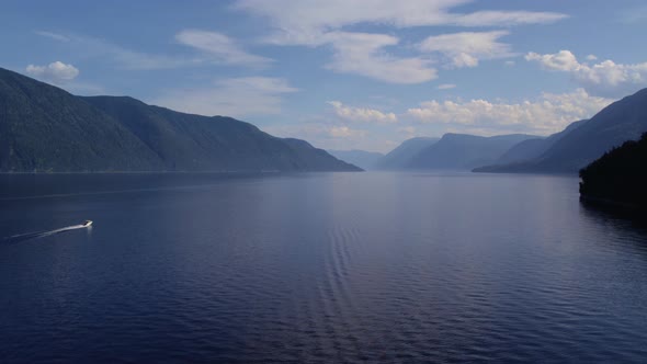 Boats on lake Teletskoye between mountains with blue clear sky in Altai