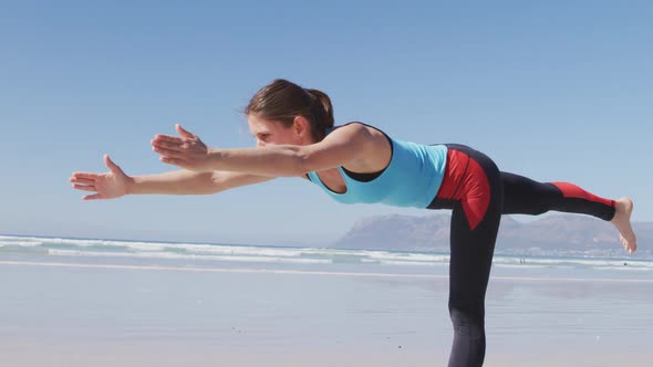 Caucasian woman doing yoga position on the beach and blue sky background