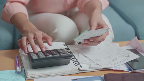 Close Up Of Woman's Hand Holding The Bill And Calculating Money By Calculator