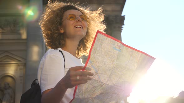 Tourist Woman Holding Traveler Map In City At Sunset