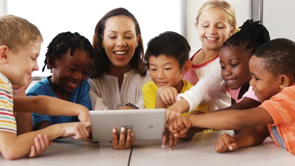 Teacher Teaching School Kids on Digital Tablet in Classroom