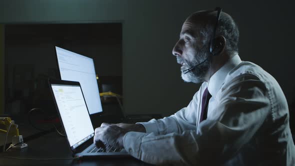 Serious Man in Headset Using Laptop