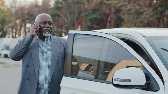 Elderly African American Man Talking on Mobile Phone Walks Up to Car Sits Down in Front Passenger