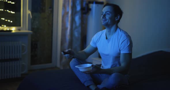 Cheerful Man Watch TV and Eating Nuts