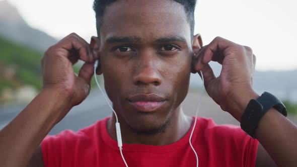 Portrait of african american man wearing earphones while standing on the road