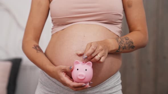 Pregnant Woman Putting Money in the Piggy Bank Closeup