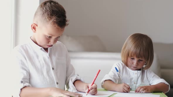 Portrait of Brother and Sister Sitting Together and Drawing at Home