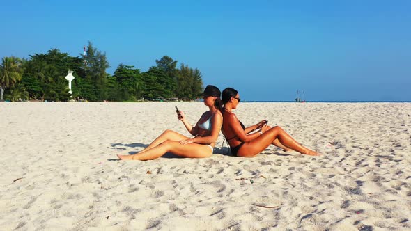 Girls posing on marine coast beach journey by blue lagoon with clean sand background of Koh Phangan 