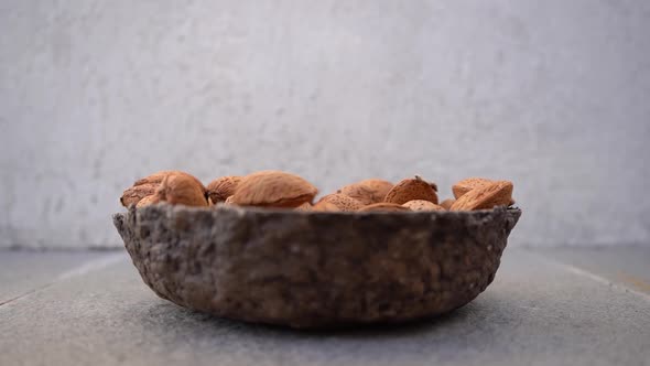 Almond Nuts In Shell Falling On Wooden Bowl. - close up