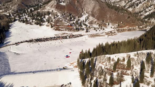 Aerial view over frozen lake with people sledding and ice fishing