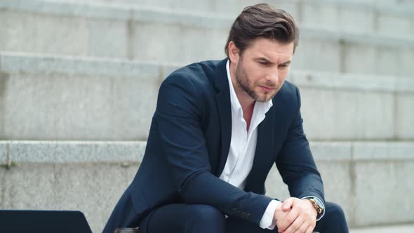 Worried Business Man Sitting on Stairs. Male Entrepreneur Holding Smartphone