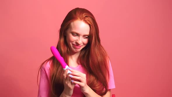 Redhaired Ginger Woman in Pink Studio Background Useing Vibrator and Feeling Embarrassment