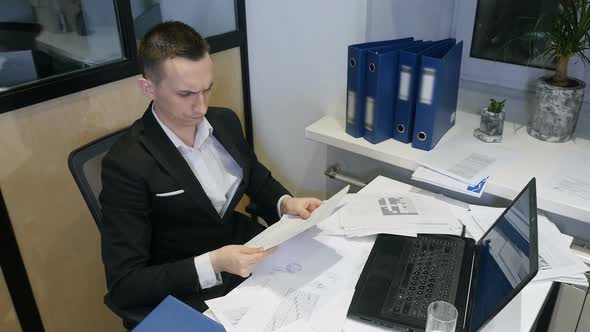 Young Businessman At Work. A Successful Manager Working With Papers and Laptop In Office.