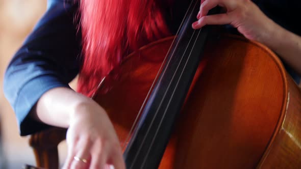 A Woman with Red Hair Playing the Cello with a Bow