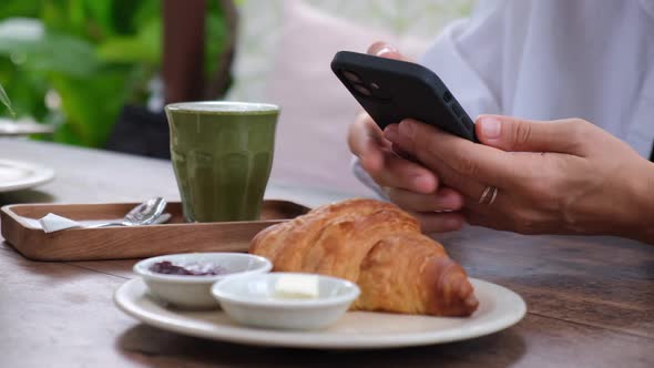 Hipster Morning in Cafe Hands Typing on the Phone Before Eating Croissant with Jam and Healthy Vegan