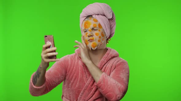 Transsexual Man in Bathrobe with Face Mask Making Selfies Using Mobile Phone
