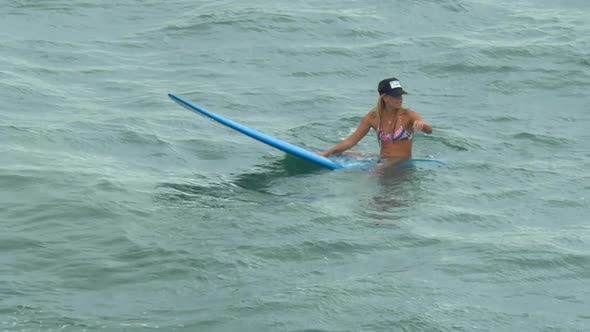 A young woman surfing in a bikini on a longboard surfboard.