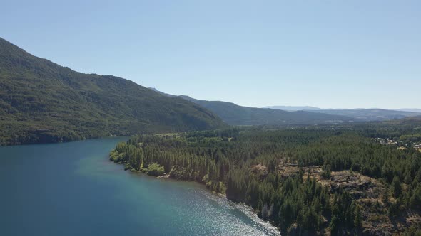 Aerial pan right over Epuyen lake between mountains and pine tree woods, Patagonia Argentina