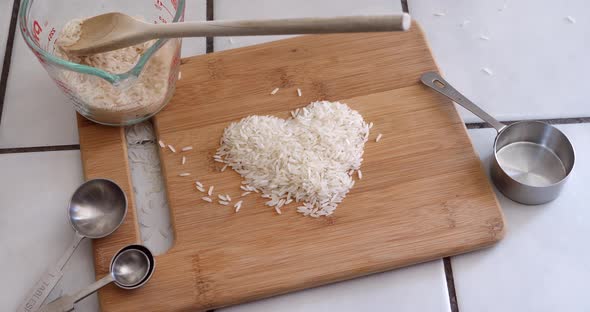 White rice grain animated forming the shape of a heart with cooking utensils and ingredients in a ki