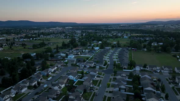 Aerial shot above middle class neighborhood as the sun begins to rise off in the distance.