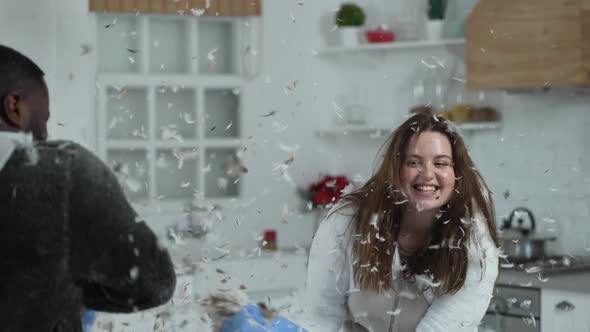 Laughing Curvy Woman Having Pillow Fight with Man
