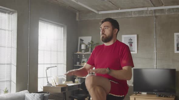 Man in Tshirt and Shorts is Energetically Jogging in Place at Home in His Spacious and Bright Living