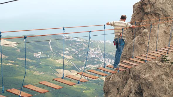 Man Walking By Suspension Bridge