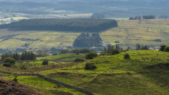 Time lapse of rural landscape with grass fields and hills during a cloudy summer day in Ireland. alt