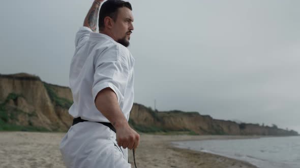 Strong Fighter Practicing Karate on Beach Closeup