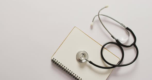 Video of close up of stethoscope with notebook on pink background