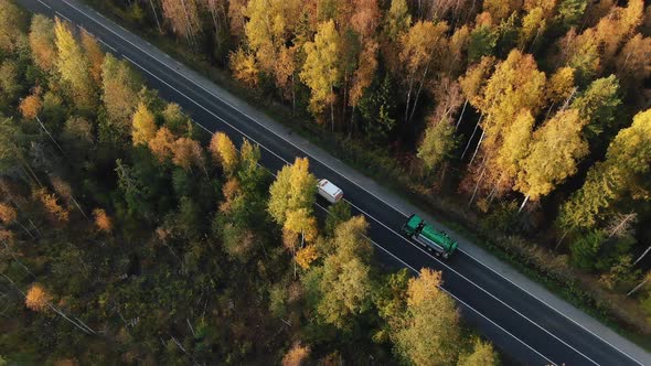 Cars Overtake Gastank Truck on Road Between Forest Trees