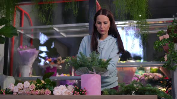 Front View Absorbed Florist Creating Bouquet Standing at Table in Workshop