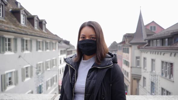 Attractive female model with respirator mask against virus infection stands in front of city of Rapp