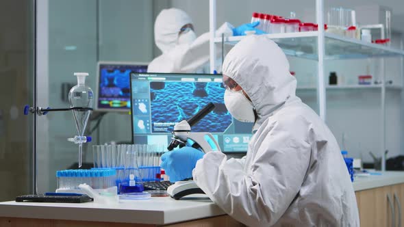 Chemist Researcher in Coverall Looking at Bacteria Sample From Glass