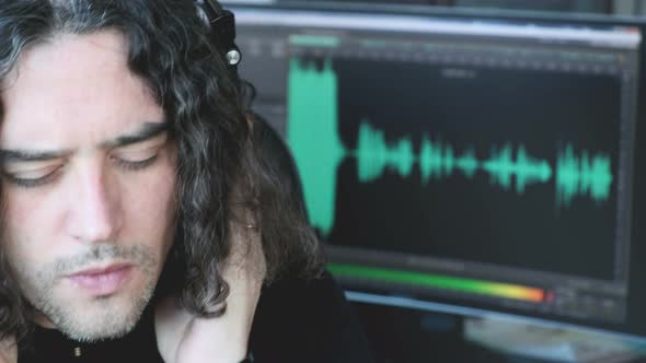 Music Composer Man with Long Hair Listen with Headphones Focusing with Audio Software Histogram in