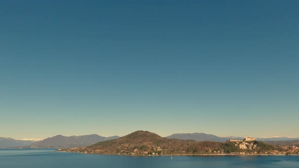 Panoramic view of beautiful lake Maggiore and Angera fortress with clear sky and boat sailing over c